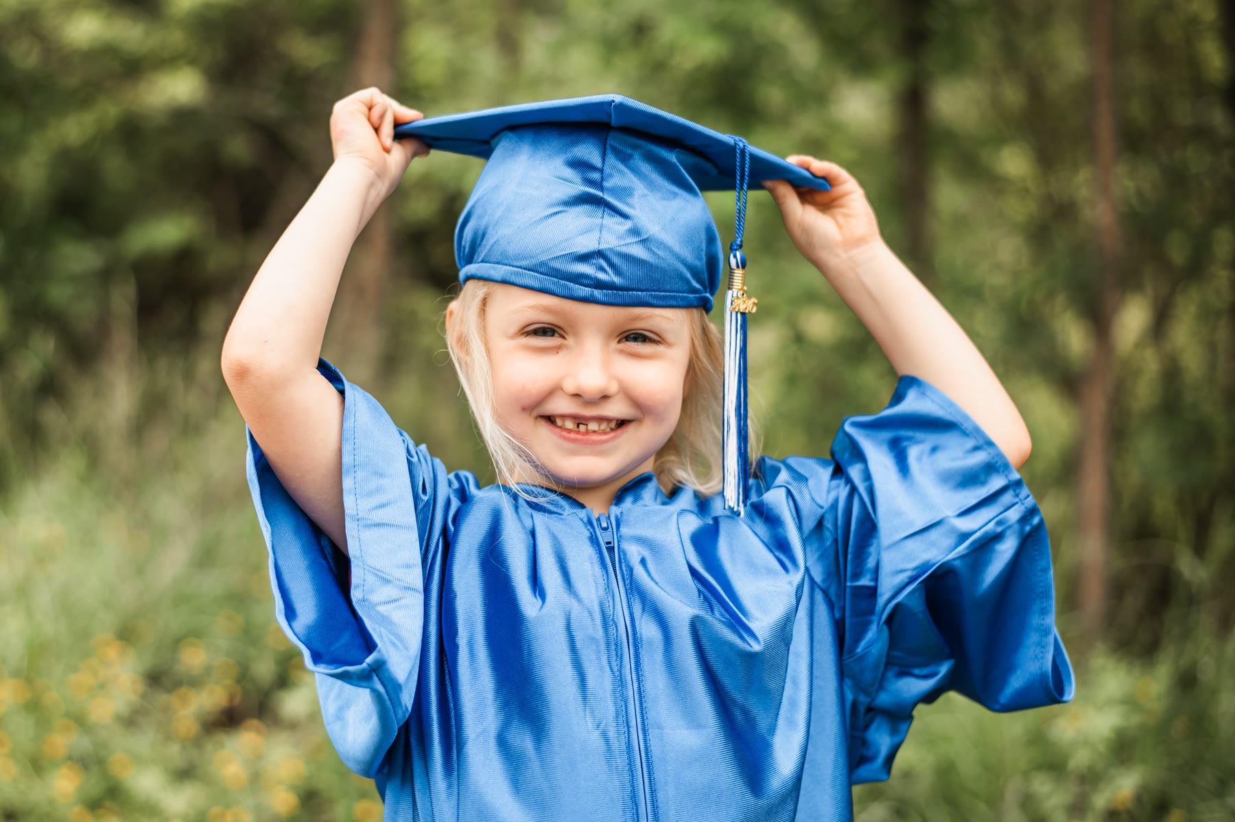 A joyful Amaze Academy graduate in a blue cap and gown